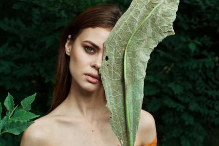 pretty woman bared shoulders green bush cosmetics cropped viewの写真素材