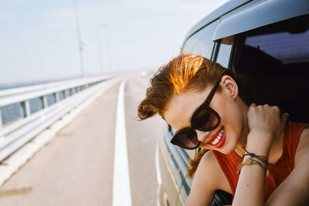 pretty woman in sunglasses rides in a travel carの写真素材