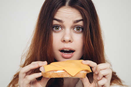 red-haired woman with a sandwich snack close-upの写真素材