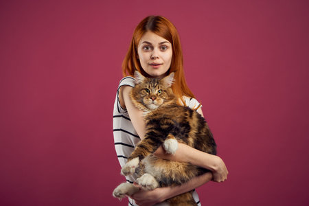 woman holding fluffy cat in her arms pet friendship pink background