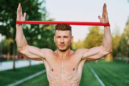 athletic man with a pumped up body in the park exercise fitnessの写真素材