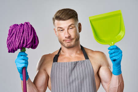 Muscled man in apron with mop posing cleaningの写真素材