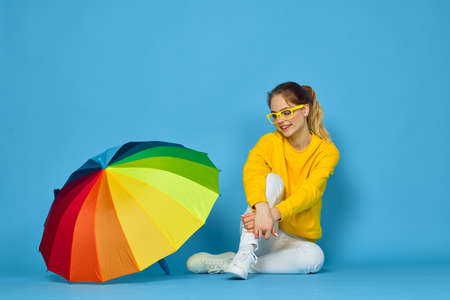 woman with multicolored umbrella in yellow sweater posing rainbow colorsの写真素材