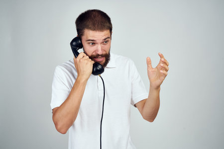 emotional bearded man talking on the phone light backgroundの写真素材