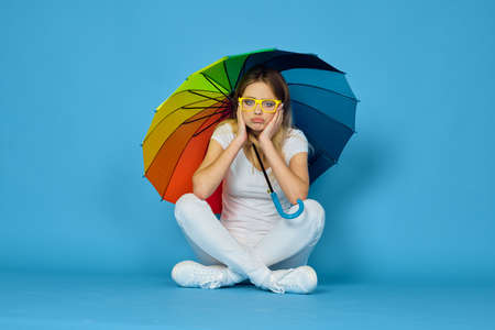 fashionable woman with umbrella rainbow colors posing blue backgroundの写真素材