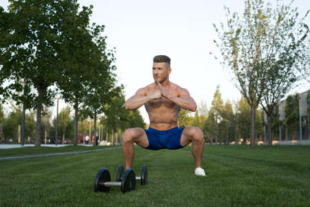 Muscled man in the park training with dumbbellsの写真素材