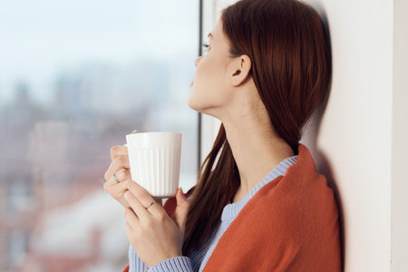 woman with hot near window in plaid rest at home