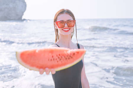 cheerful pretty woman in black swimsuit watermelon fashion travelの写真素材