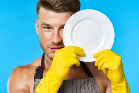 Dishwasher rubber gloves plate in hands blue backgroundの写真素材