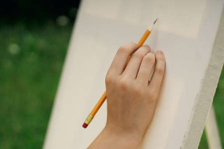 female hand with pencil easel drawing close upの写真素材