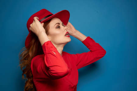 cheerful woman attractive look posing red hat blue backgroundの写真素材