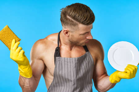 man in apron cleaning dishwashing blue backgroundの写真素材