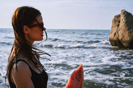 pretty woman in a black swimsuit with a watermelon in her hands summer Oceanの写真素材