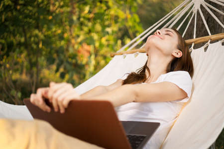 woman with laptop lies in hammock freelance travelの写真素材