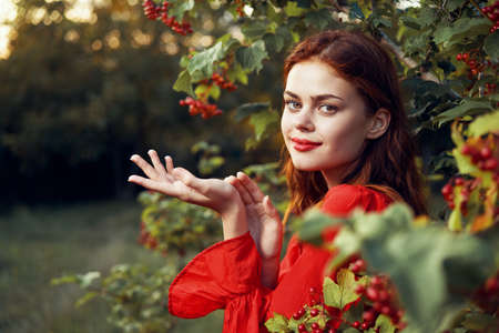pretty woman in red dress green leaves berries summerの写真素材