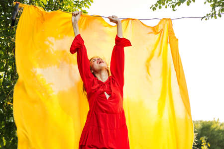 beautiful woman posing in red dress outdoors yellow clothの写真素材