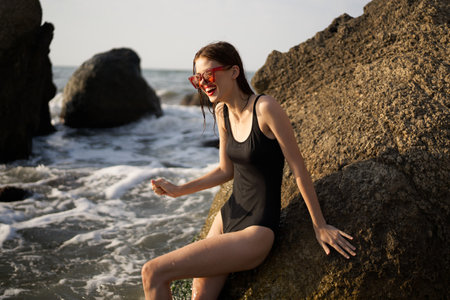 woman in black swimsuit rocks posing oceansの写真素材