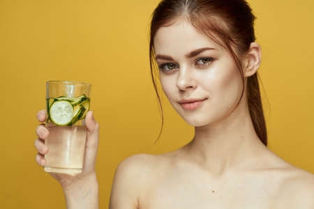 woman with cucumber drink vitamins body care yellow backgroundの写真素材