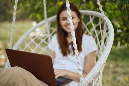 cheerful woman outdoors in hammock with laptop restの写真素材