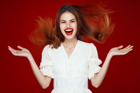 cheerful red-haired woman with red lips white dress red backgroundの写真素材