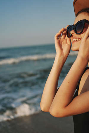 cheerful woman in sunglasses and a hat by the ocean walk summerの写真素材
