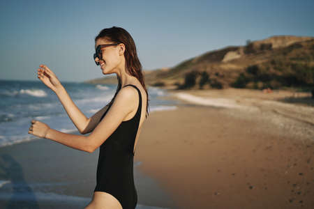 woman walks along the sandy shore in a black swimsuit sun tropicsの写真素材