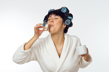 housewife in a white coat curlers on her head emotions houseworkの写真素材