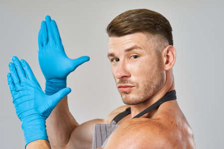 pumped up man in apron wearing rubber gloves posing cleanerの写真素材