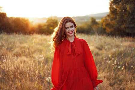 woman in a red dress in a field in nature summer landscape freedomの写真素材