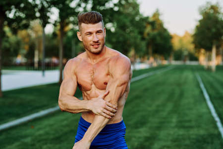 athletic man with pumped up muscular body in the park exercise workout motivationの写真素材