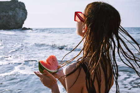 pretty woman in a black swimsuit with a watermelon in her hands summer Oceanの写真素材