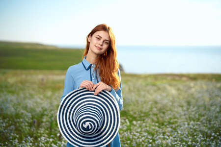 woman in a blue dress in a field in nature hat flowers walkの写真素材