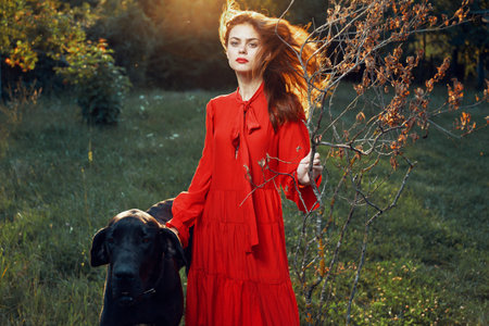 beautiful woman in a red dress outdoors with a black dog friendship
