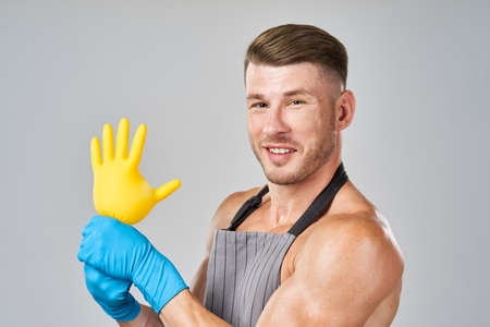 pumped up man in apron rubber gloves cleaning houseworkの写真素材