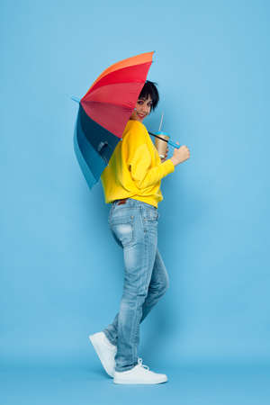 cheerful woman with rainbow colored umbrella posing street styleの写真素材