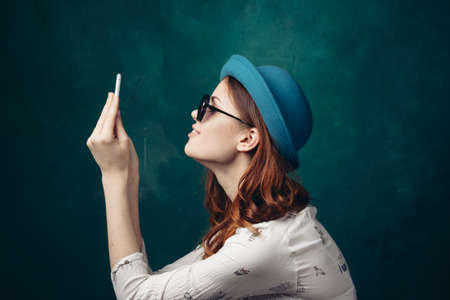fashionable woman in blue hat with phone in hands communication technologyの写真素材