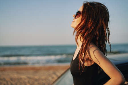woman on the beach is with a car wearing sunglasses travelの写真素材