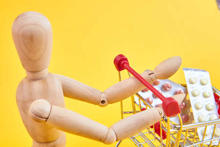 wooden dummy with medicine cart yellow backgroundの写真素材