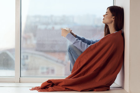 woman with hot near window in plaid rest at home