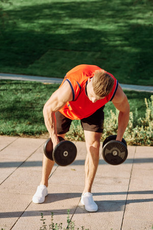 sporty man in the morning in the park with dumbbells exercise