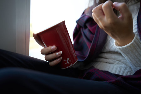 woman near window with red cup depression close-up