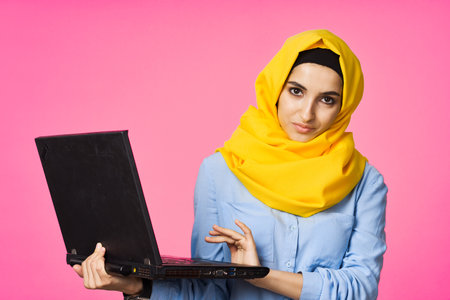 cheerful muslim woman in yellow hijab learning laptop technologyの写真素材