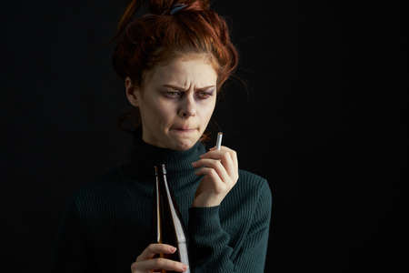 woman with bottle of alcohol bruises under eyes changes depression dark backgroundの写真素材