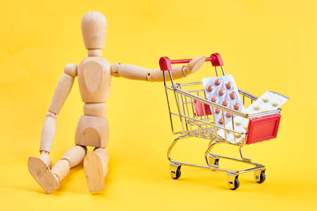 wooden dummy with medicine cart yellow backgroundの写真素材