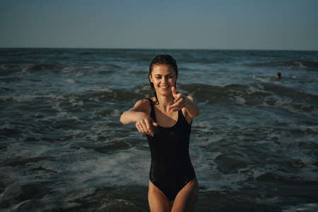 Cheerful woman black swimsuit ocean nature summer tanの写真素材