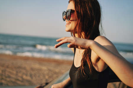 woman on the beach is with a car wearing sunglasses travelの写真素材