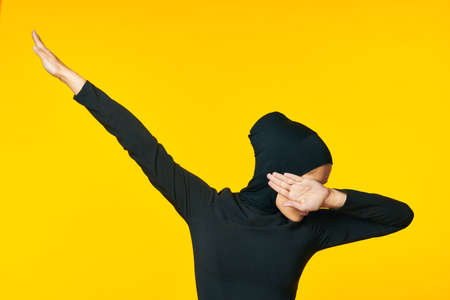 muslim woman in black hijab gesturing with her hands yellow backgroundの写真素材