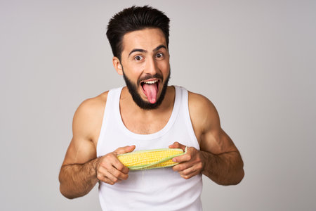 Cheerful man eating corn diet isolated backgroundの写真素材
