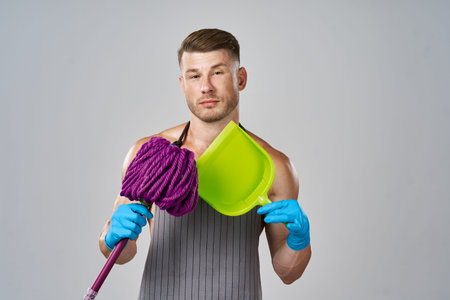 Muscled man in apron with mop posing cleaning
