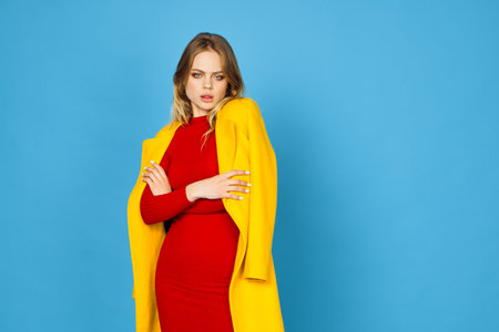 woman in yellow jacket posing makeup fashion blue backgroundの写真素材